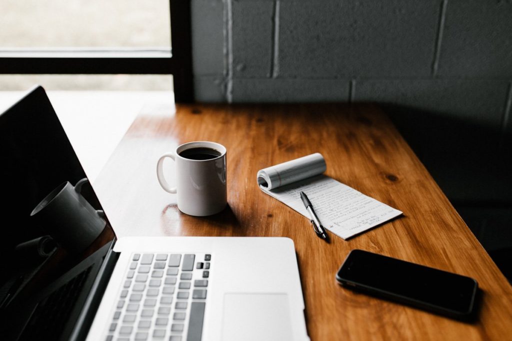 Computer, coffee, notebook, and phone, ready to plan.